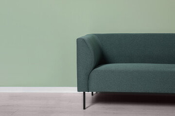 Comfortable sofa near light green wall indoors