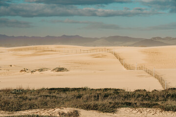 Fototapeta na wymiar Sand dunes, silhouette of mountains, and cloudy sky in the background. Abstract landscape, Oceano Dunes, California
