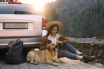 Happy woman and adorable dog sitting near car in mountains. Traveling with pet