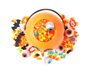Halloween trick or treat bucket with different sweets on white background, top view