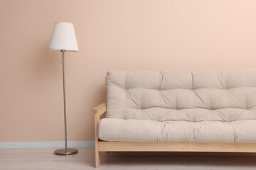 Comfortable sofa and stylish lamp near beige wall indoors