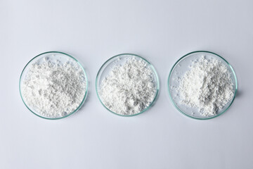 Petri dishes with calcium carbonate powder on white table, flat lay