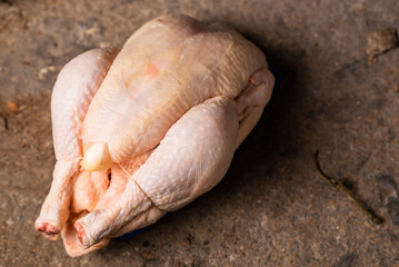 Raw shop chicken carcass on stone background. Whole chicken, preparation for cooking.