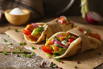 Delicious pita wraps with meat and vegetables on wooden table, closeup