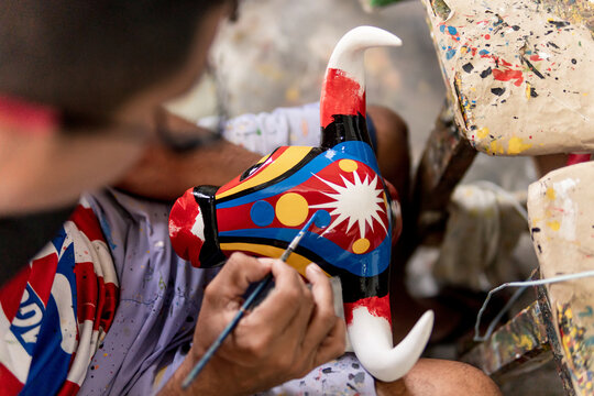 man painting bull mask carved in wood and painted with commemorative colors of the carnival of barranquilla colombia
