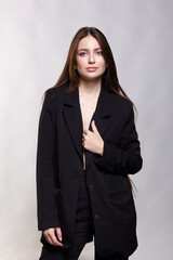 Woman in a black jacket on a gray background.