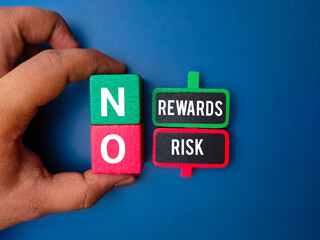 Hand holding colored cube with the word NO REWARDS RISK on blue background. Business concept.