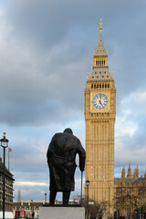 Statue of Sir Winston Churchill appearing to lean on the Elizabeth Tower of Big Ben in Central...
