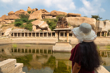 Woman tourist enjoy view of Pushkarani an ancient water reservoir at Hampi Karnataka, India.
