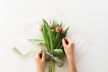 Woman's hands holding bouquet of beautiful delicate tulip flowers on white background. Bouquet of pink fresh tulips.