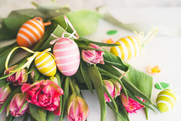 Happy Easter. Stylish dyed easter eggs with spring flowers on white background. Pink tulips with colorful eggs