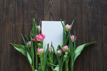 Stylish greeting card. Fresh tulips flat lay on wood background. Floral Greeting card template with...