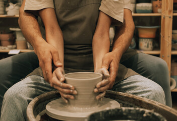 Fototapeta na wymiar Couple mold ceramic vase in a pottery workshop, hands close up.