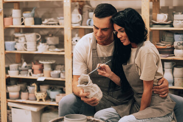 A young couple works in a pottery workshop. Painting a vase. The concept of hobbies, lifestyle and relationships. - Powered by Adobe
