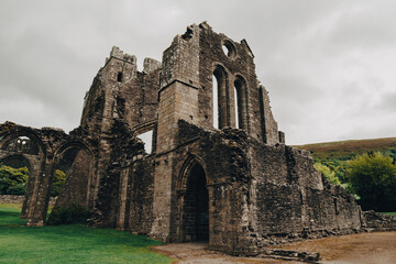 Fototapeta na wymiar Landmarks of Wales travel concept. View of ancient ruins of the castle/church in Brecon Beacons National Park, United Kingdom. Llanthony Priory Abbey in the Vale of Ewyas. Llanthony priory ruins. 