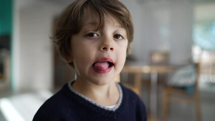 Portrait of a cute little boy sticking tongue out. Playful child looking at camera grimacing