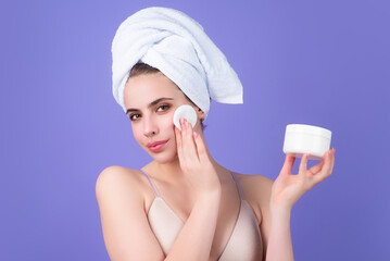 Woman removing makeup with cotton pad near face. Skin care. Girl with cotton pad, studio isolated background. Moisturizing skin by special face cream before applying foundation.