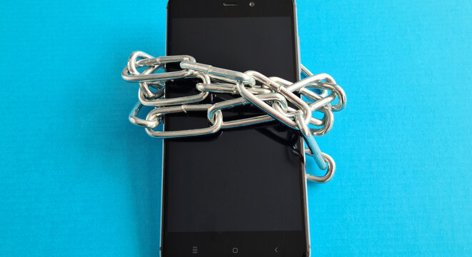 Smartphone is tied with chain on blue background