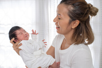 happy loving family. mother playing with her baby hugging in the bedroom , portrait of asian mother playing with newborn baby, health care family love together. asian girl lifestyle..