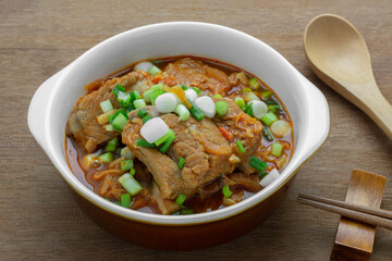 close up of pork rib braise with kimchi in a ceramic bowl on wooden table. homemade style food concept.