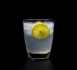 Fototapeta na wymiar lemonade with ice in crystal glass on black background