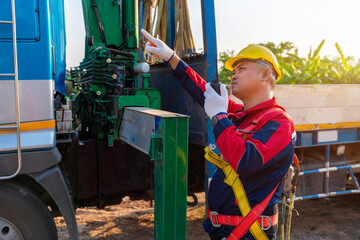 Asian supervisor or foreman is using a locator radio for a mobile crane at construction site.