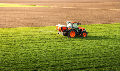 Fototapeta premium Tractor spreading artificial fertilizers in field