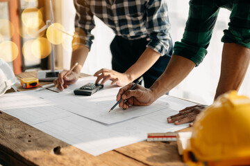 Two colleagues discussing data working and tablet, laptop with on on architectural project at construction site at desk in office