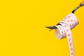 Minimal macro photography of measuring tape on fork on yellow background with copy space. Mockup...