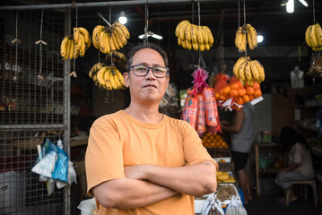 A middle aged Filipino fruit vendor, posing in front of his open-air store. A small business owner.