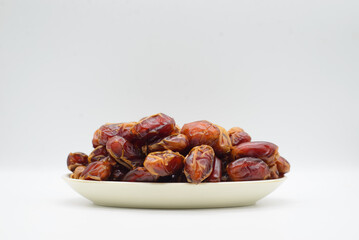 Dried dates fruit in a dish, isolated on a white background