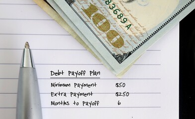 cash dollars money on note paper with text written Debt Payoff Plan - concept of setting credit...