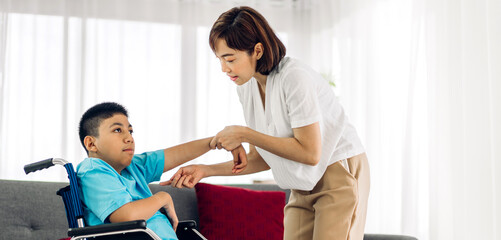 Portrait of enjoy happy love family asian mother playing and carer helping look at disabled son child sitting in wheelchair moments good time at home.disability care concept