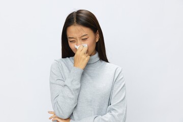 Sad Asian woman holding hand with handkerchief and coughing up flu and cold, stuffy nose viral disease asthma and allergies covid 19, white background
