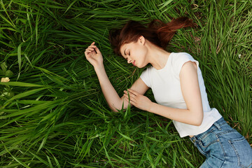 a peaceful woman lies in the grass enjoying the unity with nature