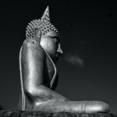 statue de Bouddha vu de profil sur un fond noir (photographie en Noir et Blanc)
