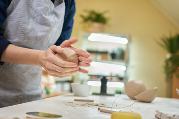 Fototapeta na wymiar Closeup hands of ceramic artist wedging clay in art studio