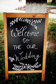 A wooden sign with a wedding invitation for holiday guests. Creative image for your design or illustrations.