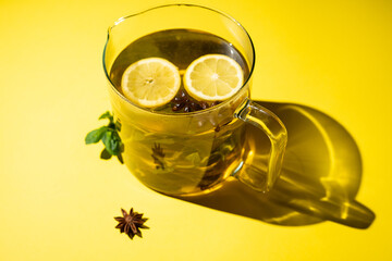 Green tea with lemon mint and star anise on a yellow background.