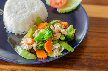 Stir fried mixed vegetables with pork or chicken tasty food, healthy food from Thailand Asia with wooden table background. side view