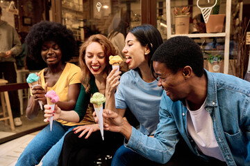 Friends licking ice cream sitting in the street