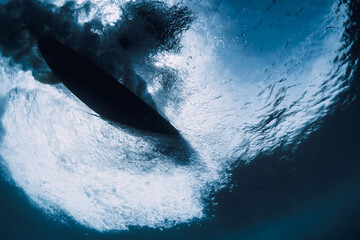 Wave underwater and surfer riding on surfboard in ocean. Underwater crashing wave and surfboard in...