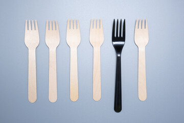 Plastic and wooden forks on a gray background. Save the ecology.