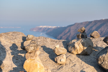 Fototapeta na wymiar Stones resting on the rock of santorini coast with Oia in the background