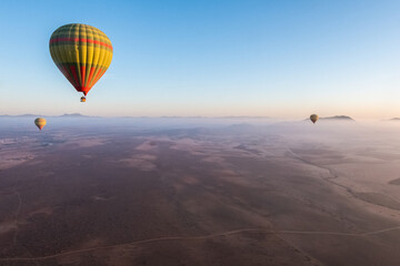 Colorful hot air balloons floating above the vast Moroccan desert expanse