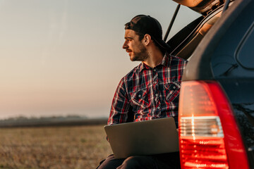 Cropped shot of a young man using a laptop while on a road trip