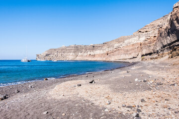 A boat anchored in a deserted beach of blue and calm waters in the island of santorini