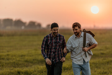 Happy gay couple having fun while moving up the hill in autumn day at sunset. Copy space.