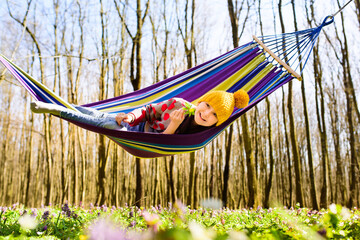 Little pretty girl resting in hammock in forest in early spring. Sunny spring day or morning.