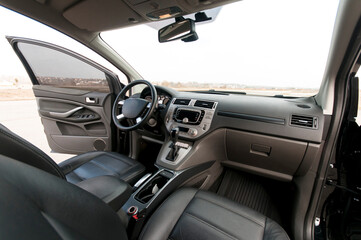 Modern car interior, black perforated leather, aluminum, details controls, leather steering wheel.